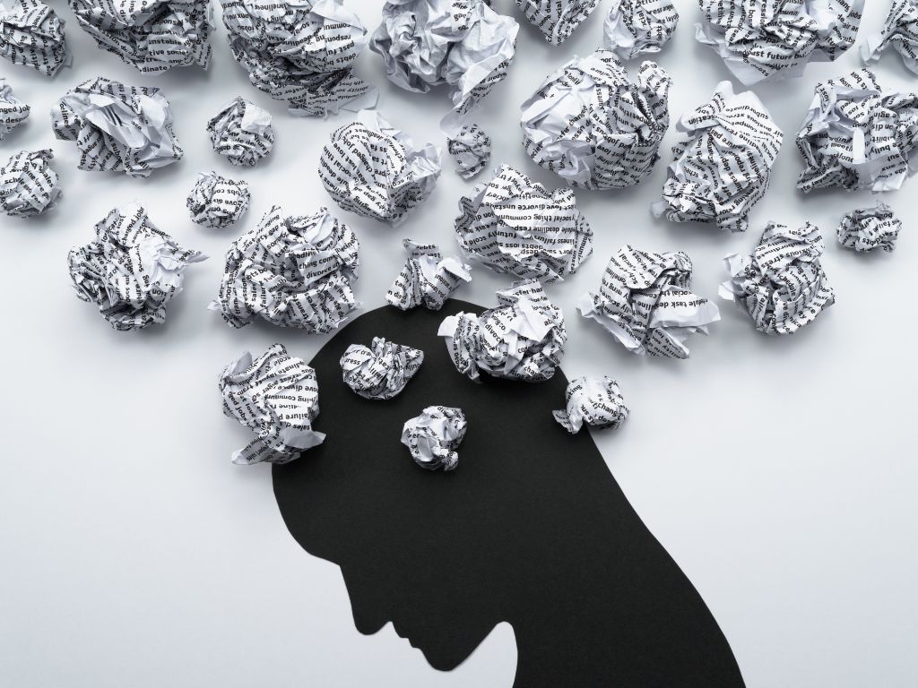 Image of a silhouette of a person's head, with crumpled paper as a troubled mind.