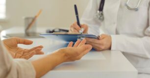 Image of consultant writing on a clipboard and patients' hands, at health assessment consultation.