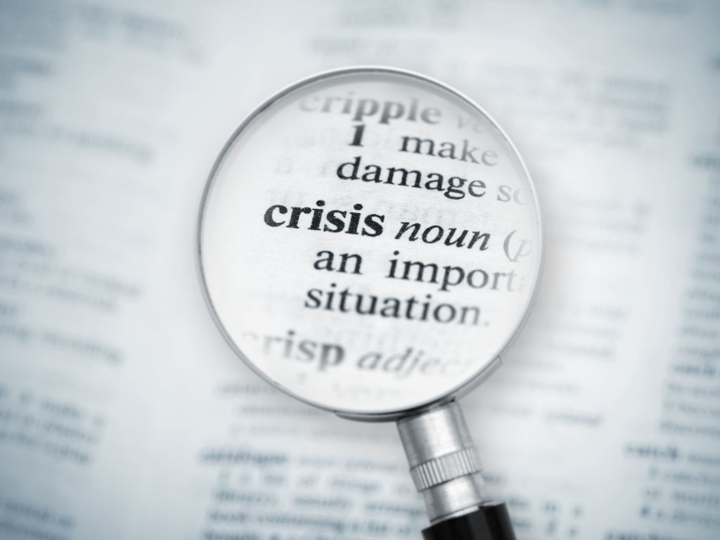 Image of a magnifying glass enlarging the word Crisis on a dictionary page